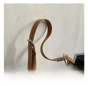 Detail of adjustable leather shoulder strap with silver buckle on a brown hobo bag