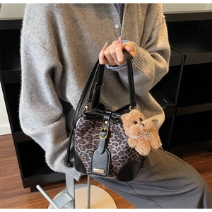 Detail of leopard print bucket bag with black leather trim and plush charm accessory