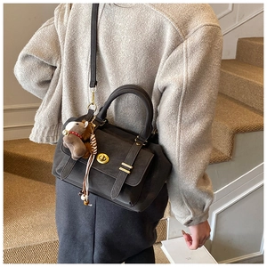 Detail of dark grey retro messenger bag with gold hardware and brown pony plush charm