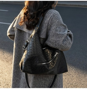 Detail of black woven leather shoulder bag with metallic zipper and large capacity