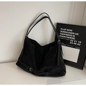 Detail view of black faux suede tote bag featuring prominent white contrast stitching