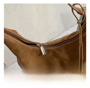 Detailed macro view of the silver metal zipper and textured brown leather on a shoulder bag