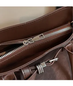 Detailed close-up of smooth silver metal zipper and stitching on dark brown leather tote