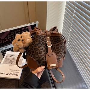 Close-up of leopard print drawstring bucket bag with leather accents and plush bear charm