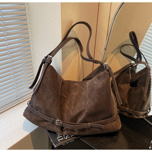 Detailed macro view of dark brown suede shoulder bag featuring silver metal buckle details