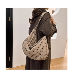 Detailed view of brown polka dot canvas hobo bag worn with a long wool coat