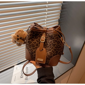 Detailed view of leopard print bucket bag with drawstring closure and brown bear charm