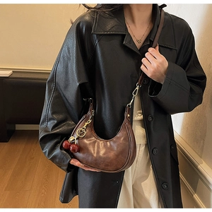 Detail of dark brown vintage crescent hobo bag with red cherry pendant charm