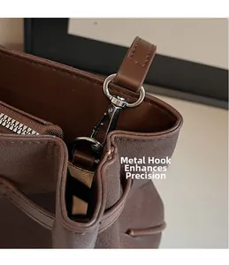 Macro view of silver metal swivel hook and litchi texture on dark brown leather bag