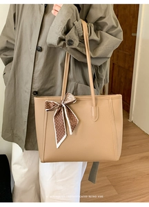 Close-up of beige lychee leather tote bag with brown polka dot scarf detail and retro vibe