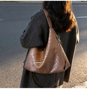 Detailed close-up of brown woven texture shoulder bag on model in soft golden light