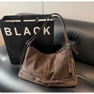 Macro shot of dark brown suede tote bag featuring retro pleats and metal buckle detail