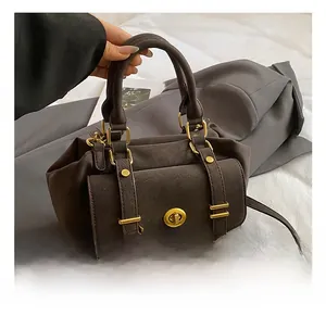 Close-up of dark brown PU leather messenger bag with gold circular twist lock and handle
