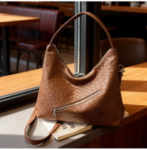 Close-up of dark brown woven leather Hobo bag featuring decorative diagonal zipper detail