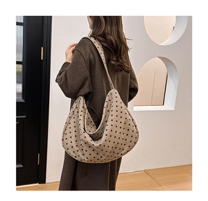 Detailed side view of a large polka dot hobo bag showing casual drape and canvas texture