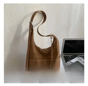 Brown leather hobo bag with front pocket detail in a modern home office setting