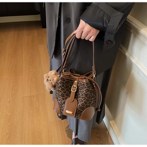 Detail of leopard print bucket bag with brown leather trim and cute teddy bear charm