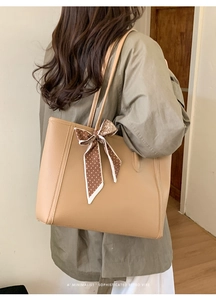Detail of apricot tote bag with lychee pattern leather and spotted silk scarf on handle
