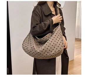 Close-up of a large polka dot tote bag styled with a brown wool coat on model