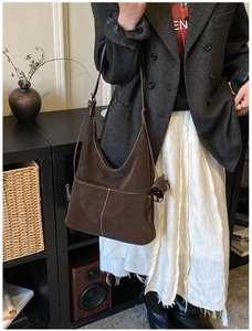 Detail view of brown leather Hobo shoulder bag with contrast stitching on a model