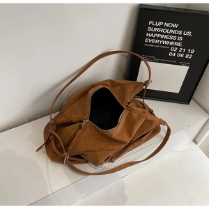 Detail view of large brown suede tote bag with slim leather straps and metal hardware