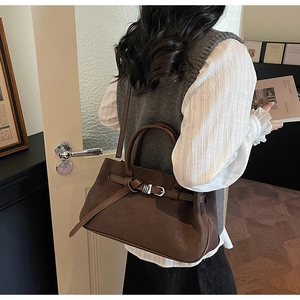 Detailed view of dark brown frosted leather tote bag with vintage strap buckle and handles