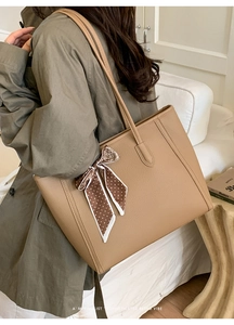Detail of khaki tote bag with textured finish and decorative polka dot silk scarf