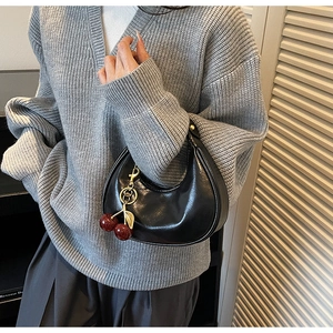 Detail of black crescent hobo bag with textured leather and cherry charm accessory
