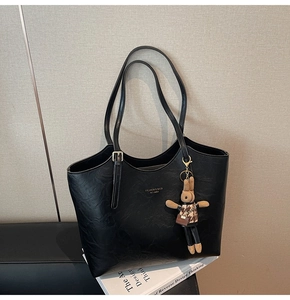 Close-up of black retro tote bag with textured faux leather and a cute rabbit charm