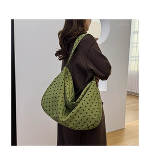 Detail of soft green canvas tote bag featuring stylish black polka dots on shoulder