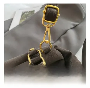 Close-up of premium golden metal swivel hook and buckle on a vintage messenger bag