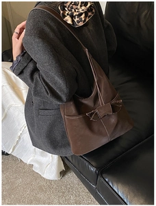 Detail of dark brown hobo bag with contrast white stitching and leather strap detail