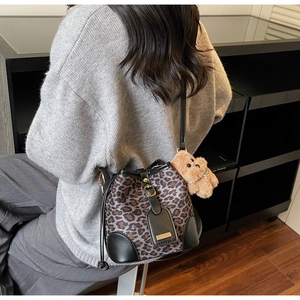 Detail of leopard print bucket bag with black leather base and cute plush bear charm