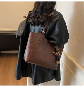 Detail of vintage brown tote bag with retro oil wax leather texture and rabbit charm