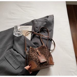 Macro detail of leopard print bucket bag with brown leather base and adjustable strap