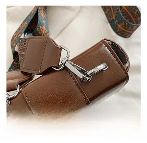 Détail de la boucle en métal argenté et de la bandoulière tissée du sac en cuir