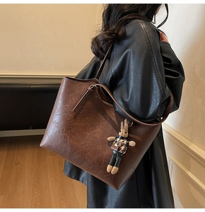 Close-up of vintage brown tote bag with textured leather and cute rabbit charm