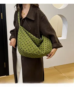 Detailed texture of green corduroy shoulder bag with black polka dot patterns