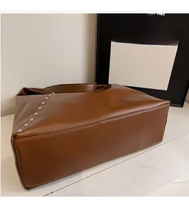 Detail view of brown leather tote bag featuring side silver metal rivet decorations