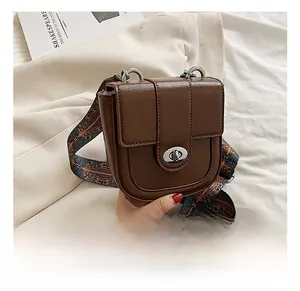 Détail du sac bandoulière marron foncé avec large sangle ethnique et fermoir rotatif argent