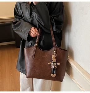 Detail of vintage brown tote bag with retro leather texture and a rabbit doll charm
