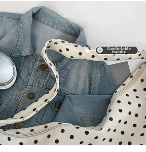 Detail view of the wide canvas strap and smooth zipper on a polka dot tote bag