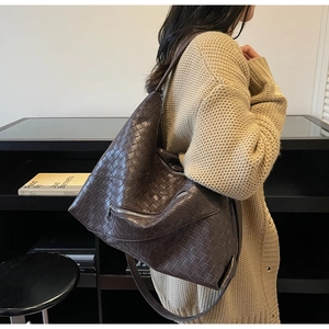 Detailed side view of dark brown woven tote bag showing texture and silver zipper detail