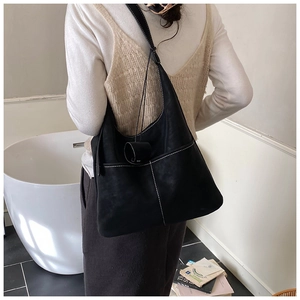 Detail of black large capacity hobo bag featuring contrast white stitching and side pocket