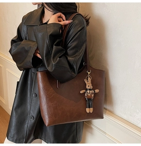 Detail of vintage brown tote bag with plush bunny charm and smooth matte texture finish
