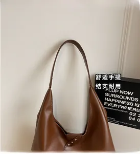 Detail of dark brown leather tote bag showing silver metal rivets and matte texture
