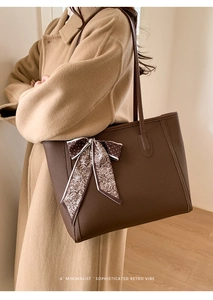 Close-up of brown leather tote bag with decorative paisley silk scarf and bow detail