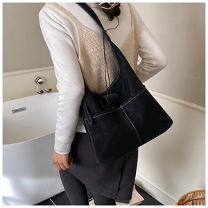 Detail of black leather tote bag featuring contrast white stitching and soft texture