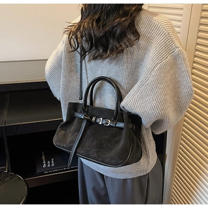 Detailed view of black matte tote bag with leather buckle strap on shoulder of a model