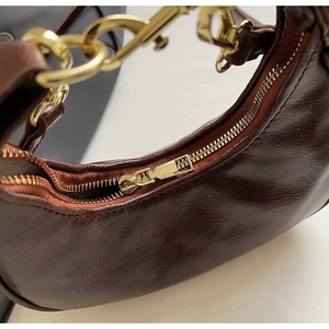Close-up of vintage dark brown crescent bag with pebble leather texture and gold zipper